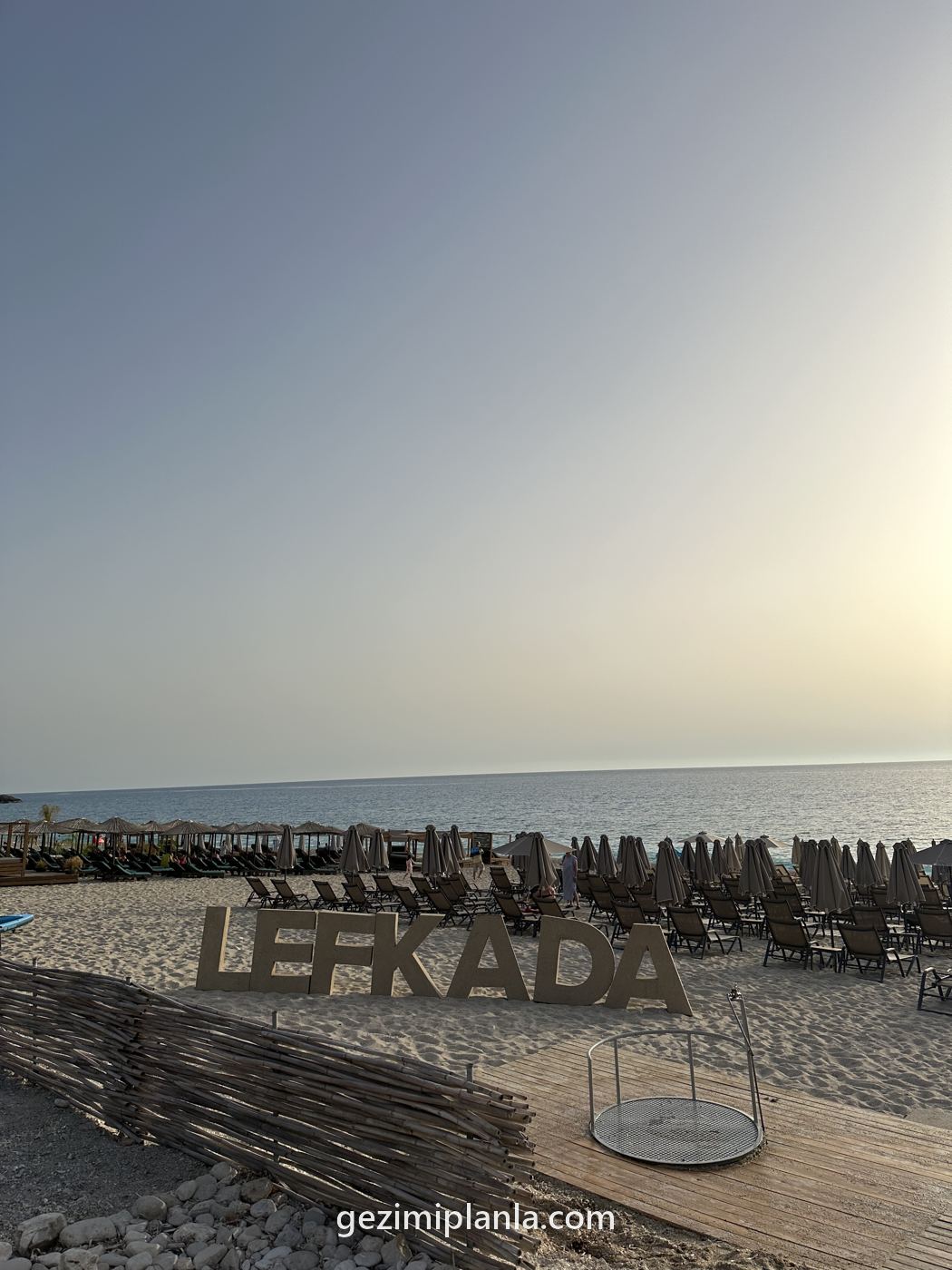 Kum üstünde LEFKADA yazısı ve gün batımı